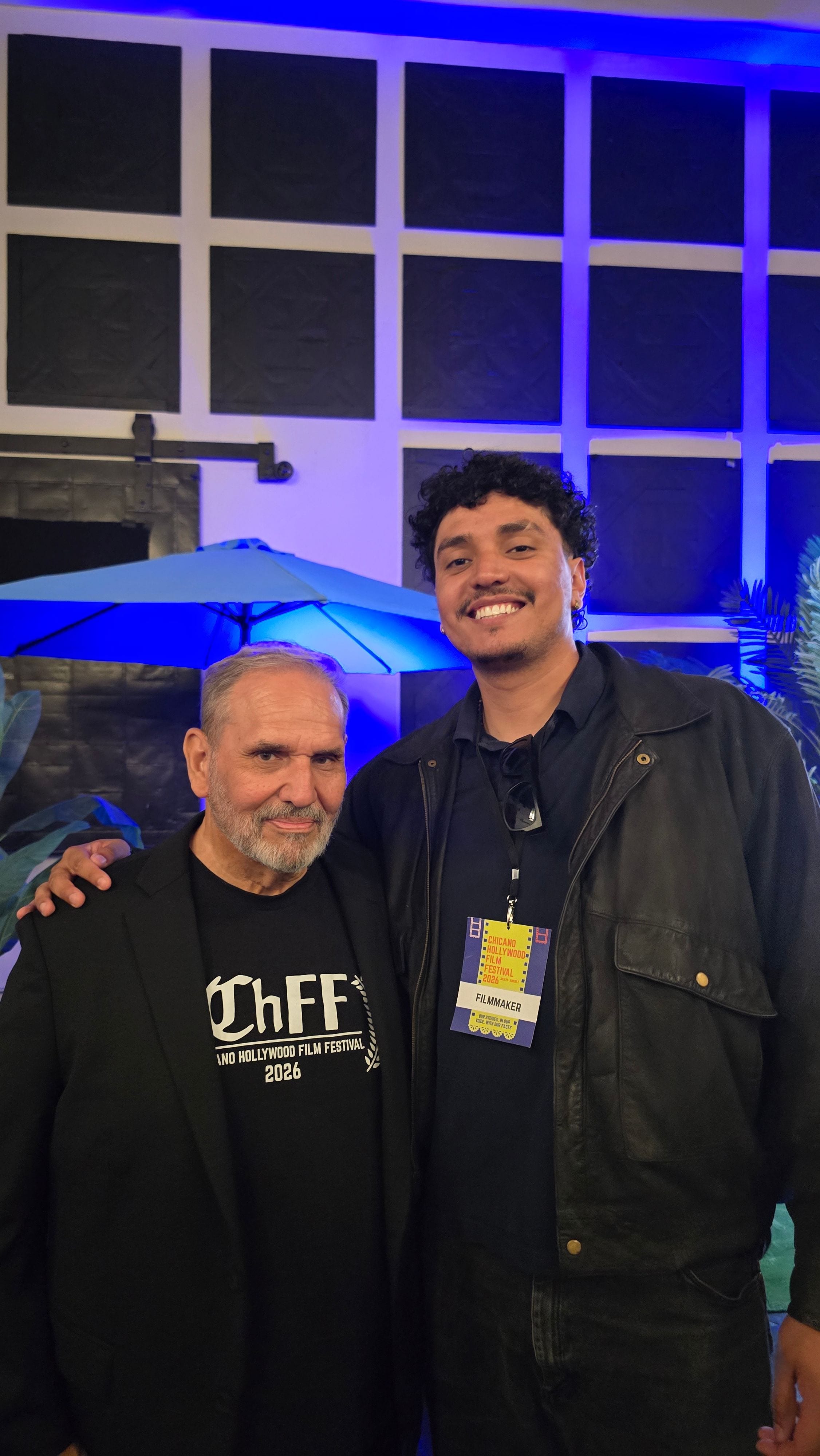 José Alfredo Alvarez with a film festival attendee in a blue-lit venue.