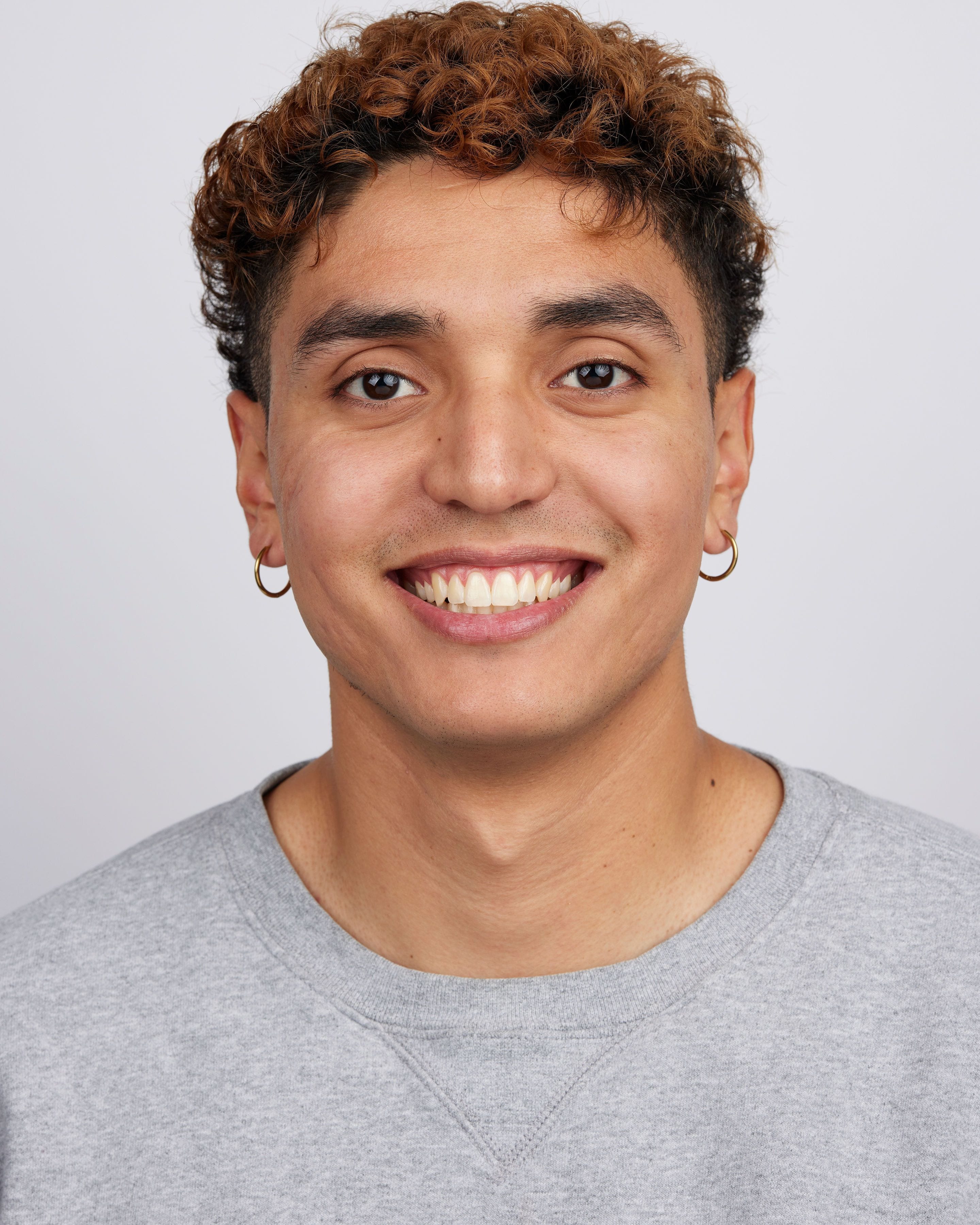 Smiling headshot of José Alfredo Alvarez in a gray crewneck shirt.