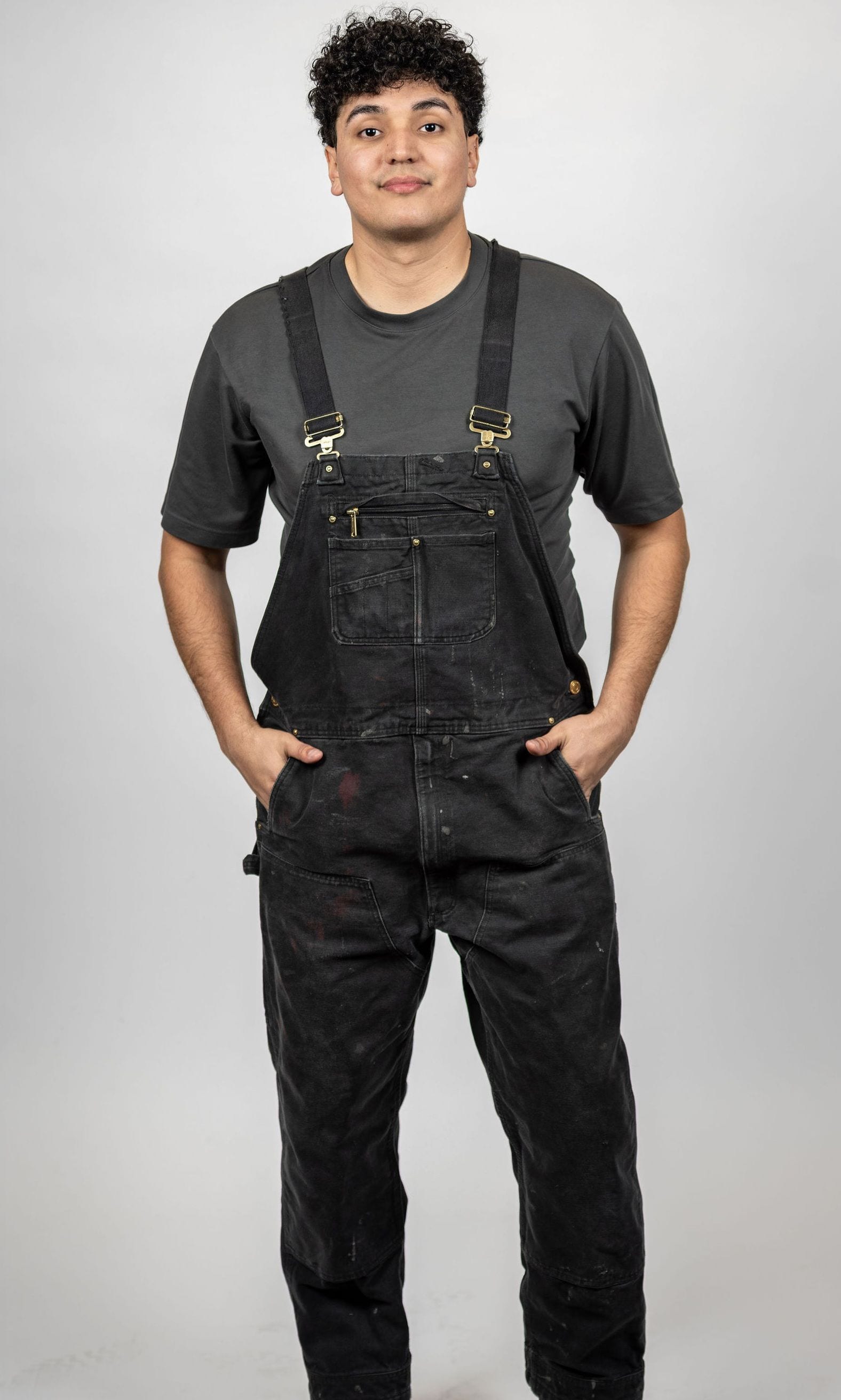 Full-body studio portrait of José Alfredo Alvarez wearing black overalls.