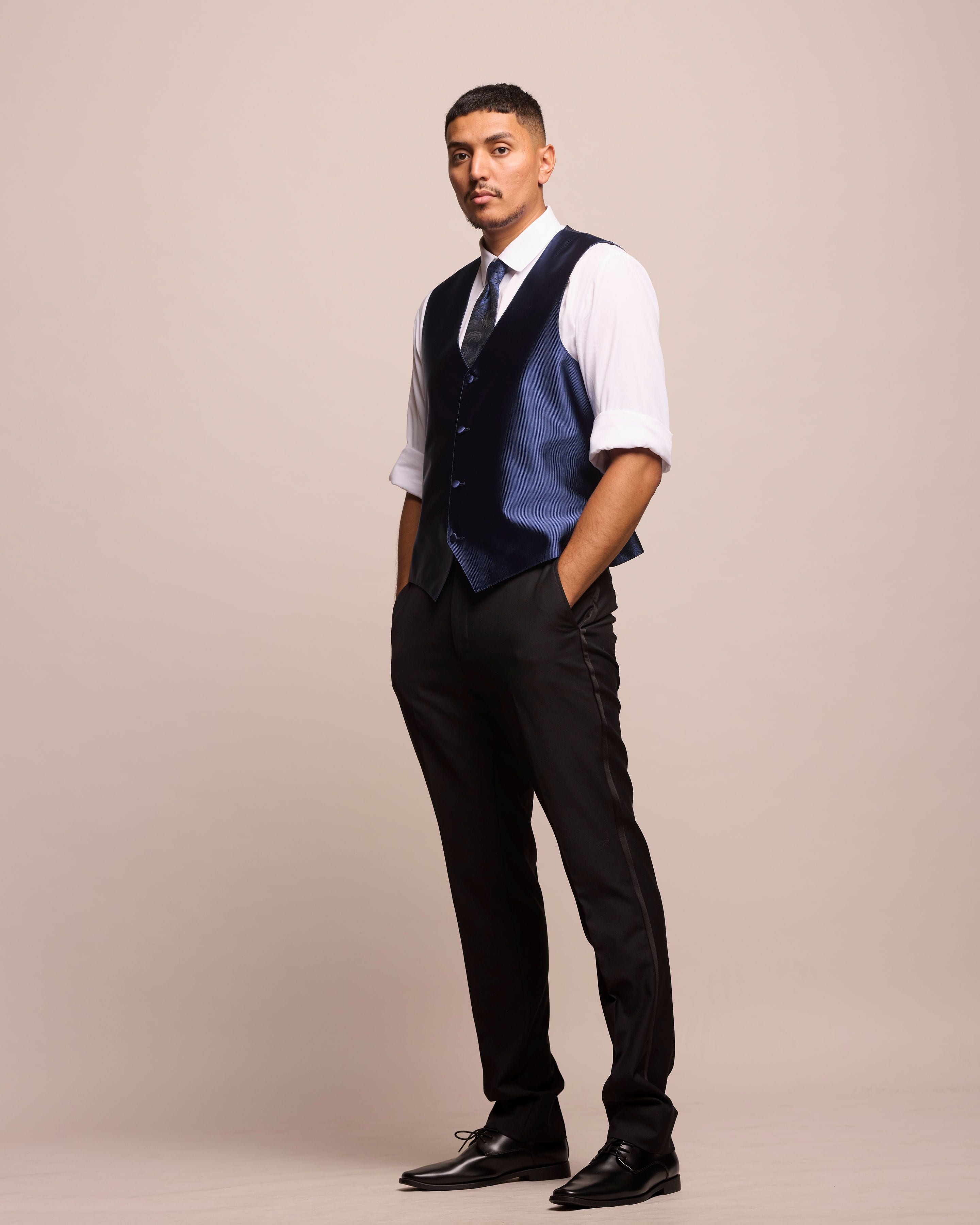 Full-body studio portrait of José Alfredo Alvarez wearing a vest and tie.