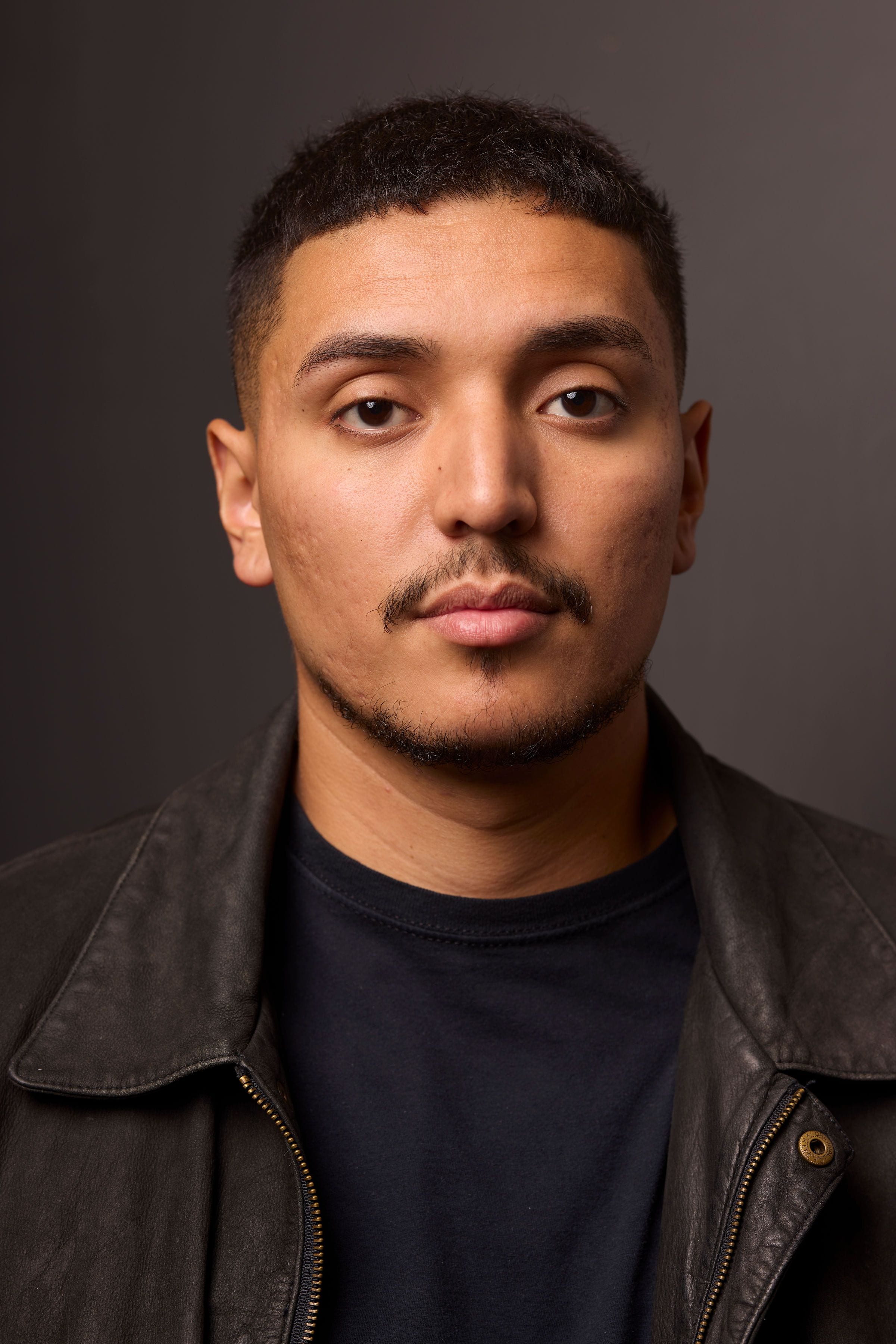 Close portrait of José Alfredo Alvarez in a black leather jacket against a dark background.