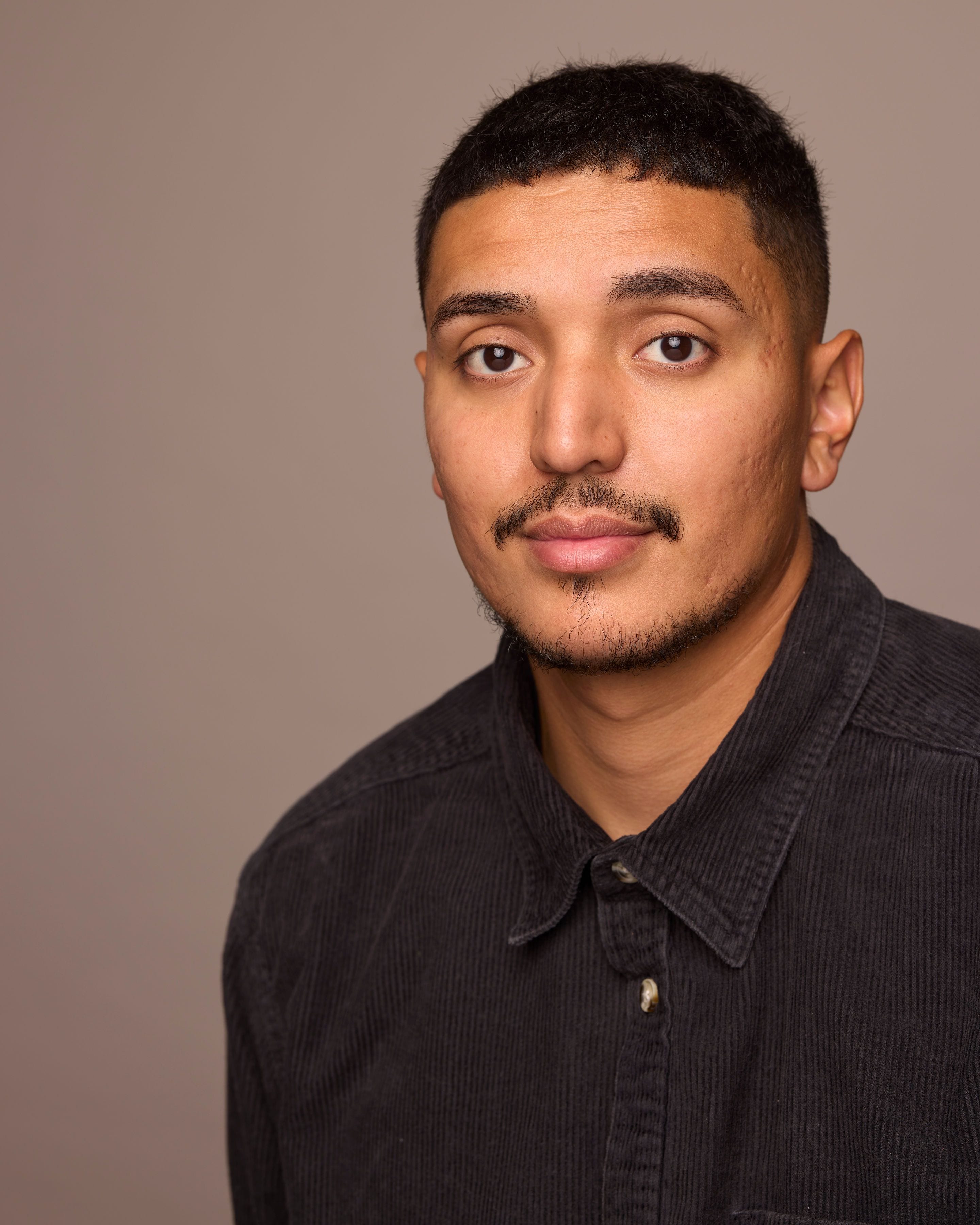 Headshot of José Alfredo Alvarez with a mustache in a dark button-up shirt.